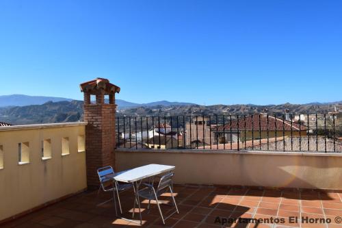 a table and chairs on a balcony with a view at Apartamentos Horno y Casa De Dulce in Purullena