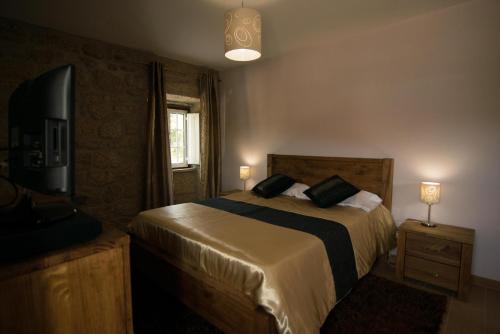 a bedroom with a bed and a television and a window at Quinta da Pedra Grande in Monsanto