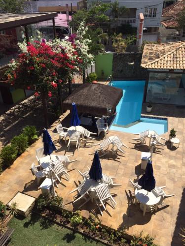 a group of chairs and umbrellas next to a pool at Pousada Alice in Cabo Frio