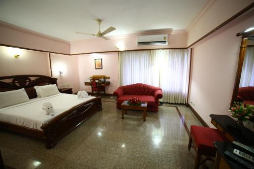 a hotel room with a bed and a chair at Mayura Residency in Guruvāyūr