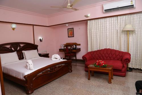a bedroom with a bed and a red couch at Mayura Residency in Guruvāyūr