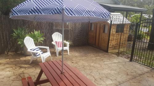 two chairs and a table with an umbrella on a patio at Casa Husky in Huskisson