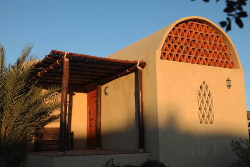a small church with an arch and a palm tree at Nomada hotel in La Ventana