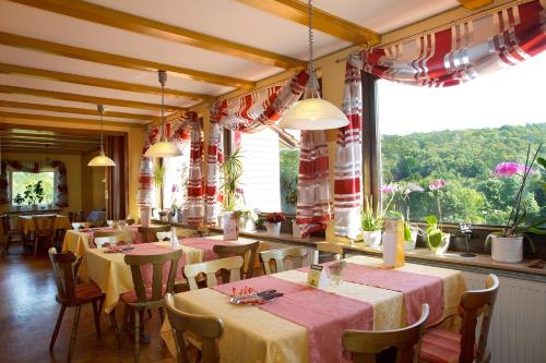 un restaurant avec des tables et des chaises et une grande fenêtre dans l'établissement Gasthaus Trifelsblick, à Wernersberg