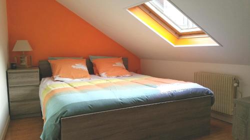 a bedroom with a bed with an orange wall and a window at Le Duplex in Honfleur