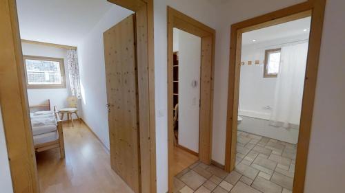 un corridoio con due porte e una stanza con tavolo di Pavrella a Celerina