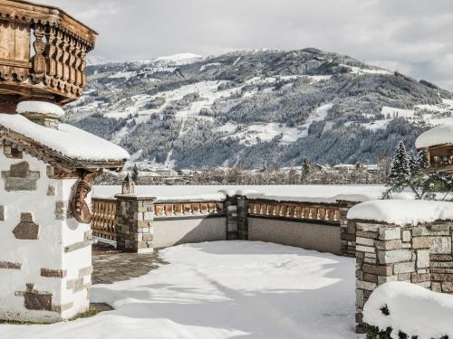 a house covered in snow with a mountain in the background at Tirol Appartement Haus Zillertal in Zell am Ziller