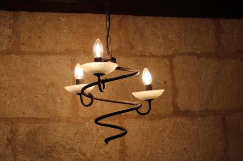 a chandelier with three lights hanging from a brick wall at Les Glycines in Remoulins