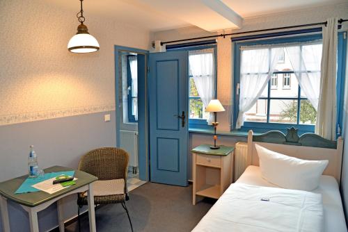 a bedroom with a bed and a desk and a table at Pension zum Brauhaus in Stralsund