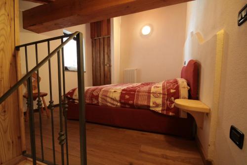 Un pequeño dormitorio con una cama y una escalera en Appartamenti Peroulaz, en Charvensod