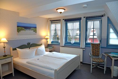 a bedroom with a bed and a desk and windows at Pension zum Brauhaus in Stralsund