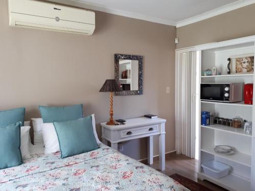 a bedroom with a bed and a table and a mirror at Melsetter's Guesthouse in Bloemfontein