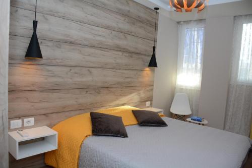Central Luxury Apartment في تيرانا: غرفة نوم بسرير مع جدار خشبي