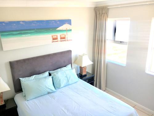 アマンジムトティにあるHightide Apartmentのベッドとビーチの絵が飾られた寝室