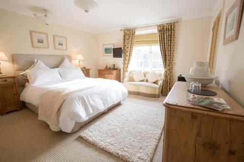 a bedroom with a large white bed and a chair at Court Barton Farm in Aveton Gifford