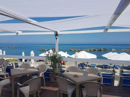 a restaurant with tables and chairs and a view of the ocean at B&B Rometta Beach in Rometta Marea