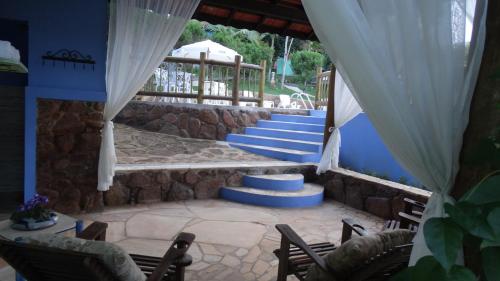 a patio with a stone wall and blue stairs at Pousada Cheiro da Terra in Cunha