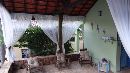 a patio with white curtains and chairs in a room at Pousada Cheiro da Terra in Cunha