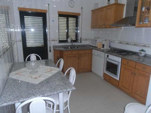 una cocina con armarios de madera y una mesa con sillas. en calmo e simpatico apartamento, en Vila Praia de Âncora