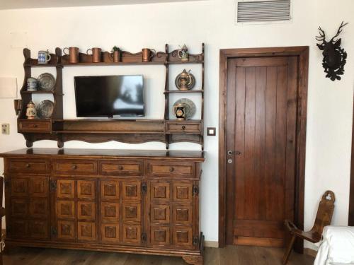 uma televisão num armário de madeira num quarto com uma porta em Appartamento em Madonna di Campiglio