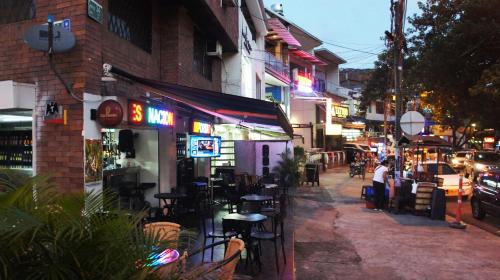 a city street at night with people sitting outside a restaurant at Hotel Parque del Perro in Cali