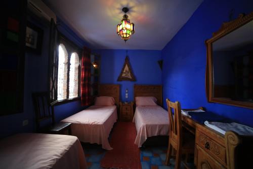 a blue room with two beds and a mirror at Dar Lbakal in Chefchaouene