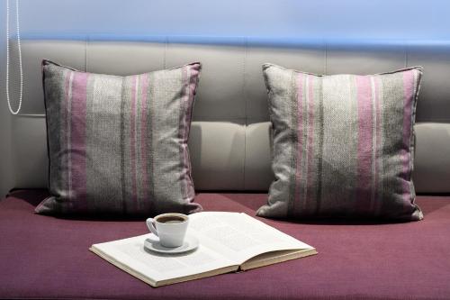 a cup of coffee and a book on a bed with pillows at Gkeea Boutique Hotel in Ierissos