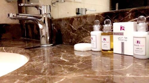 La salle de bains est pourvue d'un lavabo et de bouteilles de savon. dans l'établissement Beach Inn, à Al Qunfudhah