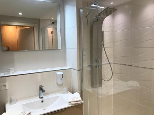 a bathroom with a shower and a sink and a mirror at Au Soleil, Hôtel Restaurant & Spa in Valff