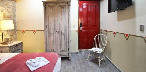 a bedroom with a bed and a red door and a chair at Alondra Hotel Boutique in Mineral del Monte