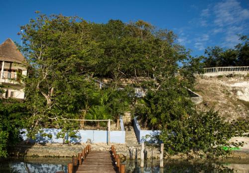 a wooden bridge over the water next to a house at El Roble Nature Hotel & Lagoon in Bacalar