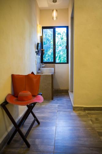 an orange chair in a bathroom with a sink at El Roble Nature Hotel & Lagoon in Bacalar