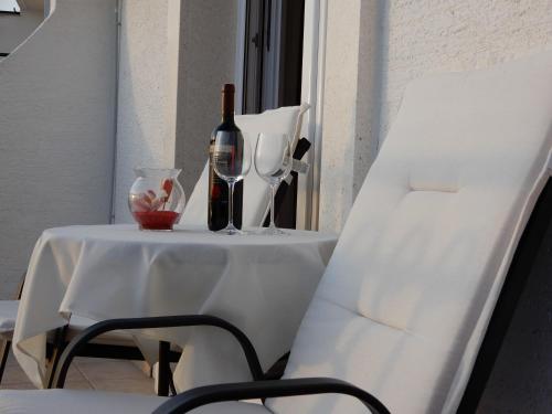 a white table with a bottle of wine and two glasses at Apartment Wind Rose in Baška Voda