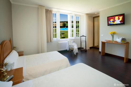 a hotel room with two beds and a television at Balneario Palacio de las Salinas in Medina del Campo