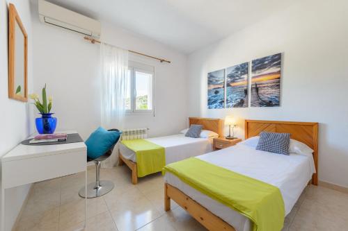 a bedroom with two beds and a desk and a table at Villa Can Prats in Santa Eularia des Riu