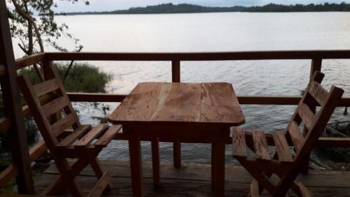 a wooden table and two chairs on a deck overlooking a lake at Cabañas Cielo Azul in Isla Mancarron