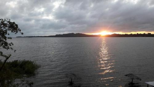 a sunset over a large body of water with umbrellas at Cabañas Cielo Azul in Isla Mancarron