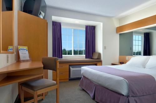 a hotel room with a bed and a desk and a window at Microtel Inn & Suites by Wyndham Plattsburgh in Plattsburgh