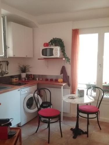 une cuisine avec une table, deux chaises et un four micro-ondes dans l'établissement Studio à 2 pas du Palais, à Cannes