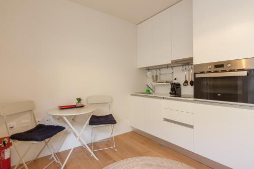 eine Küche mit weißen Schränken und einem kleinen Tisch in der Unterkunft Secret Camões in Porto