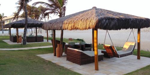 a patio with chairs and umbrellas on the beach at Atlantic Palace Family inn in Aquiraz