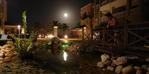 a man sitting on a fence near a pond at night at Atlantic Palace Family inn in Aquiraz