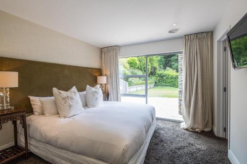 a bedroom with a large bed and a large window at Riverview Retreat Holiday Home by MajorDomo in Queenstown