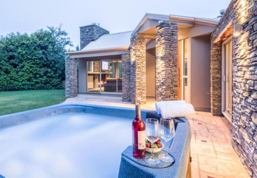 a swimming pool with a bottle of wine and glasses at Riverview Retreat Holiday Home by MajorDomo in Queenstown