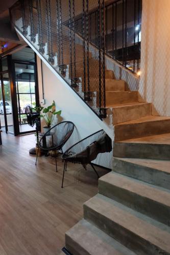 a lobby with a staircase with two chairs and a table at La Malila Hostel in Udon Thani