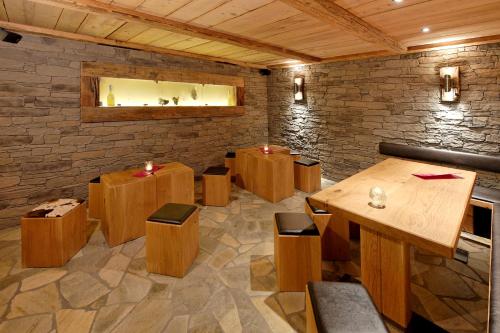 a restaurant with wooden tables and chairs and a stone wall at Hotel Walliserkanne in Grächen