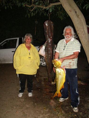 a man and a woman holding a fish next to a statue at COEMBOTA Cabañas in Tigre