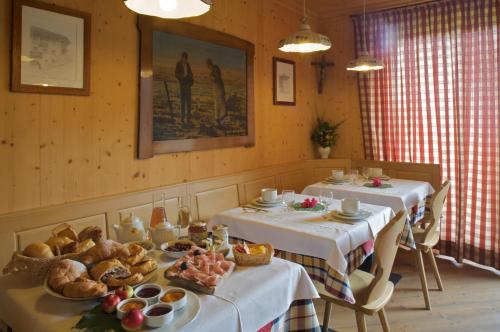 una sala da pranzo con due tavoli con pane e dolci di B&B Affittacamere Larix a Rumo