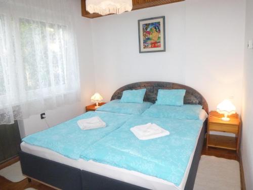 1 dormitorio con 1 cama azul y 2 toallas en Oleander Holiday House, en Siófok