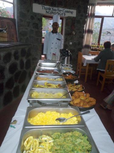 a buffet line of food with a chef standing behind it at Sora Lodge Lalibela in Lalībela